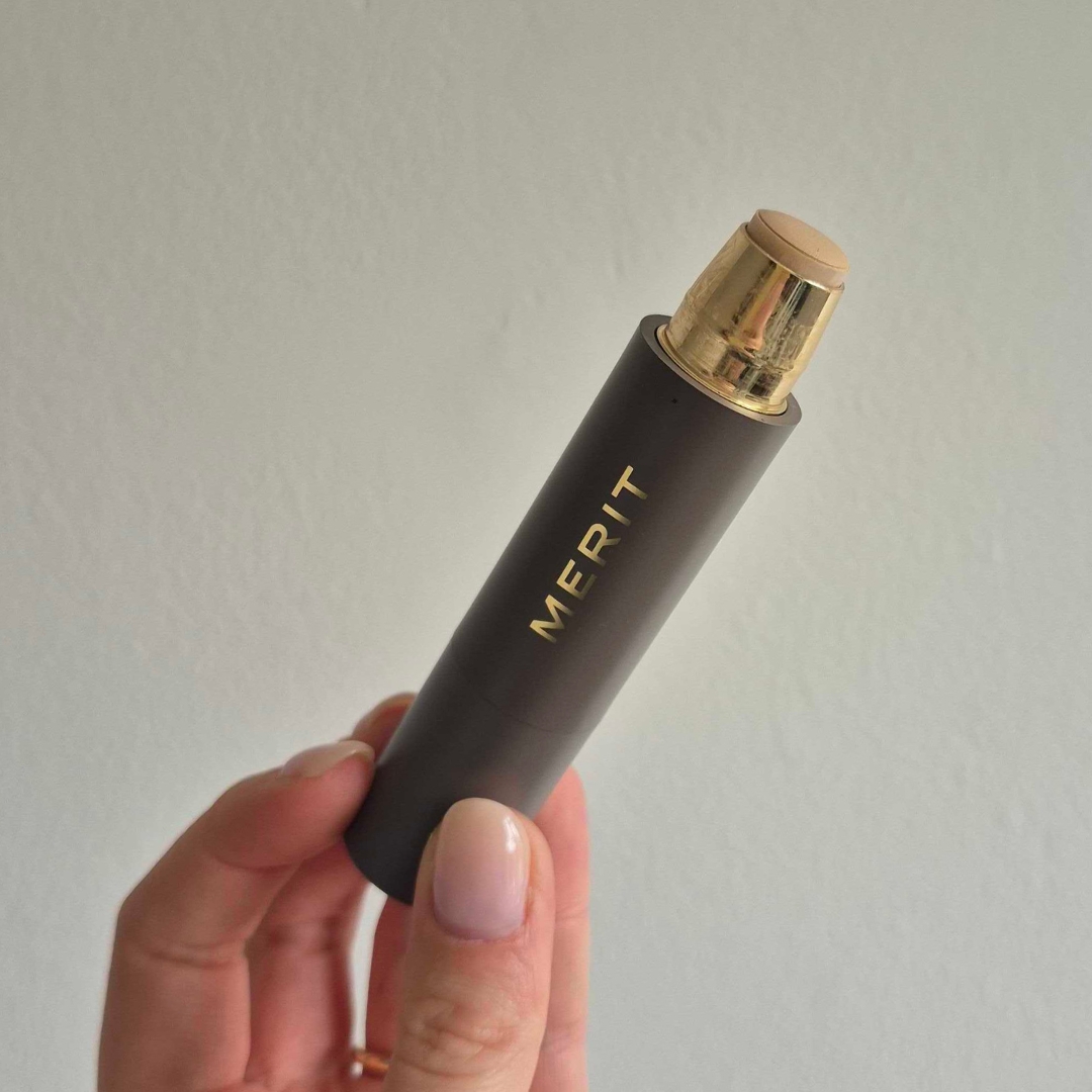 Hand holding empty stick of the Merit Beauty The Minimalist Foundation Stick