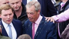 George Cottrell (L) looks on as Reform UK party leader Nigel Farage reacts after a woman threw what appeared to be a milkshake over him