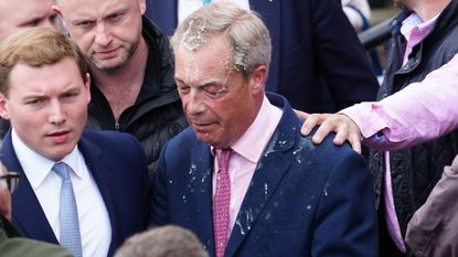 George Cottrell (L) looks on as Reform UK party leader Nigel Farage reacts after a woman threw what appeared to be a milkshake over him