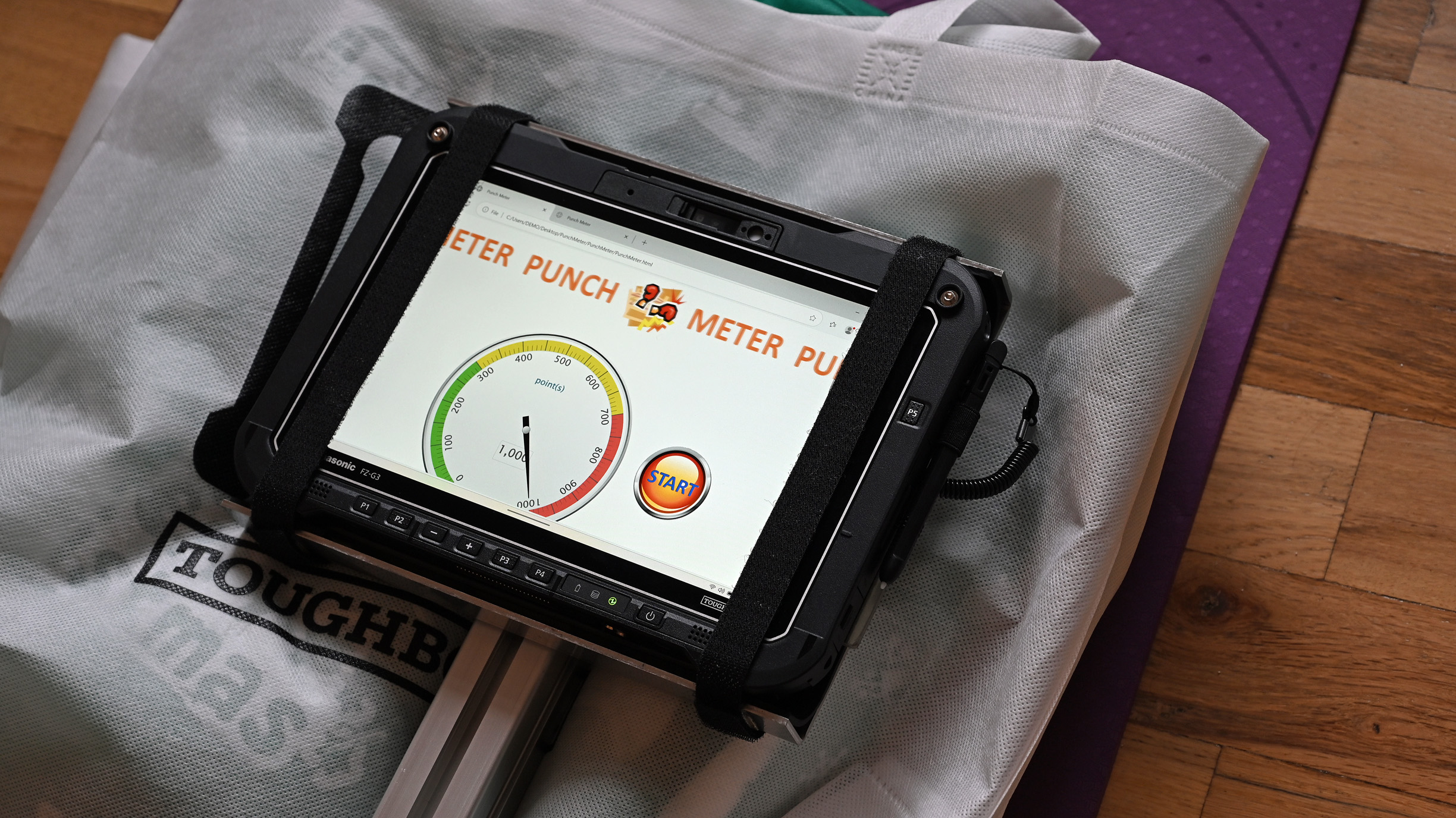 A Panasonic TOUGHBOOK G3 tablet secured in a corner-strap harness, showing a punch meter app on the touchscreen.