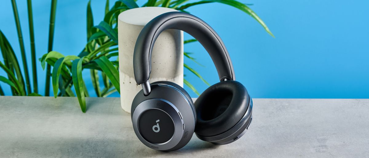 the soundcore space one pro headphones; a photograph of a pair of black over-ear headphones with cushioned cups and a soft headband, photographed in front of a blue background