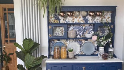 Kitchen dresser painted blue with floral wallpaper backing