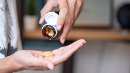 Person is pouring Vitamin tablets onto their hand