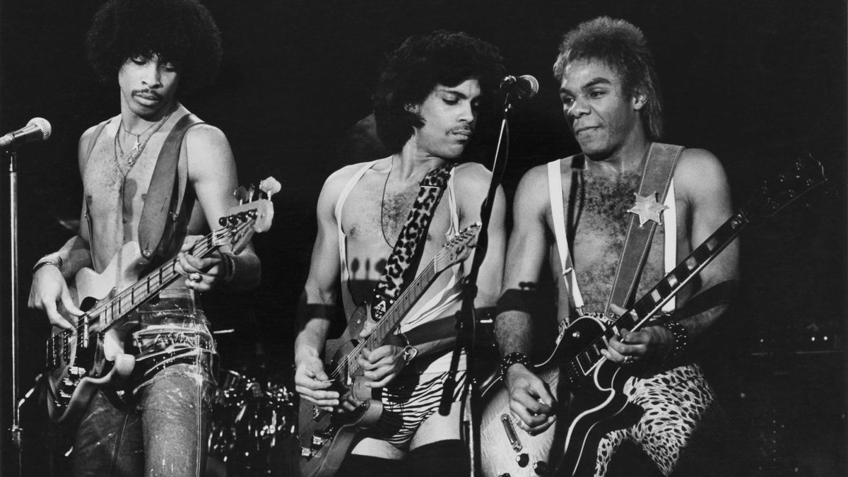 Prince, playing his T-style Hohner guitar, performs with Dez Dickerson (right) playing a Les Paul, and André Cymone (left) playing a Jazz bass