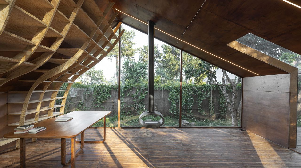 Wooden cabin with curving bookselves and glass window