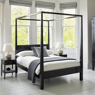 Canton black four poster wooden bed in white bedroom
