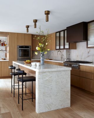 quartz kitchen island bench with timber and metal upper cabinets and black bar stools