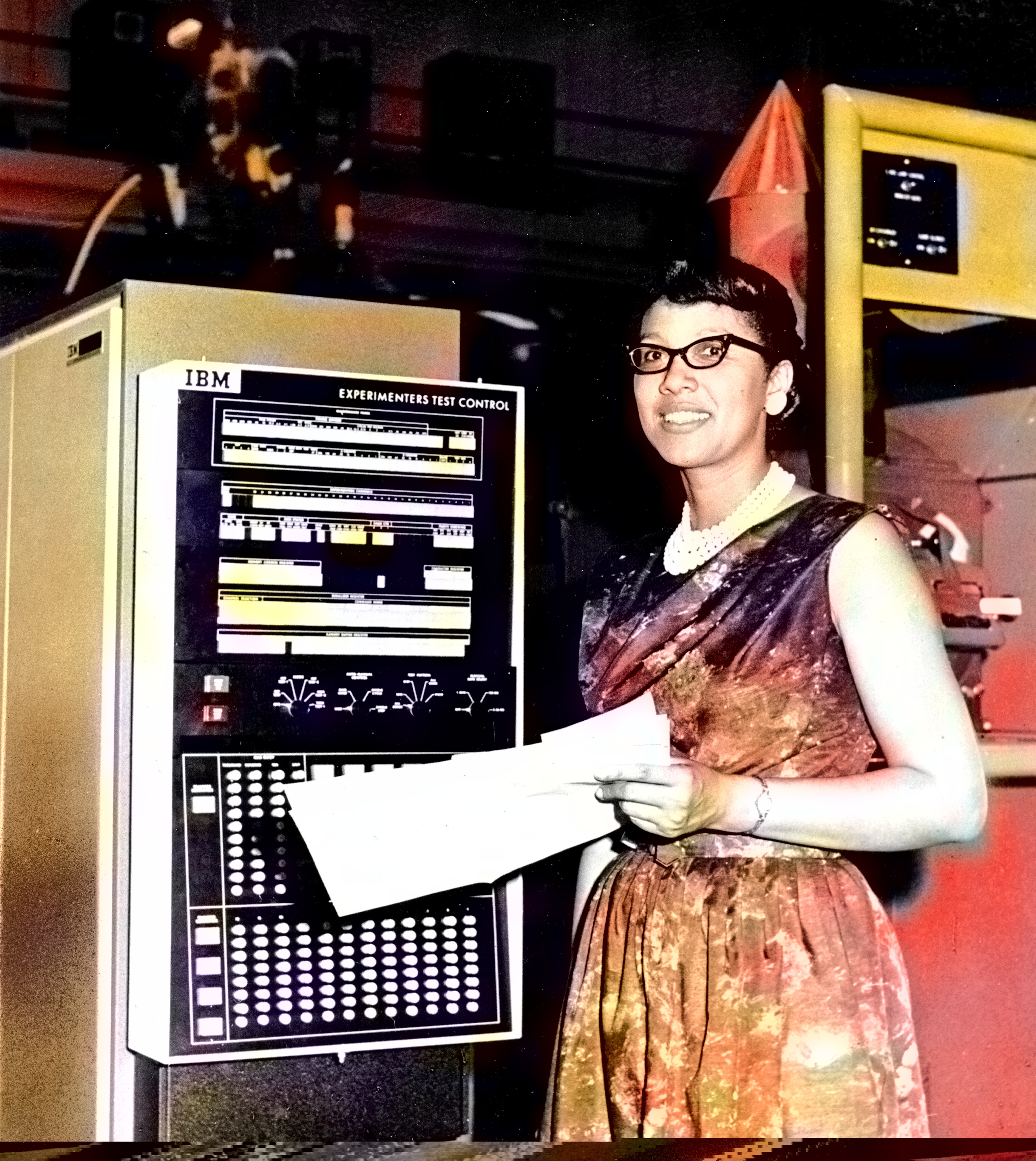 Digital color photo of Melba Roy Mouton standing next to a large computer at NASA headquarters in 1964