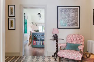 hall with pink armchair and wine table with kitchen doorway and mint green island unit