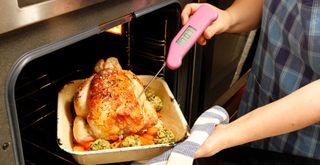 cooking a whole chicken in an oven using a meat thermometer to cook thoroughly