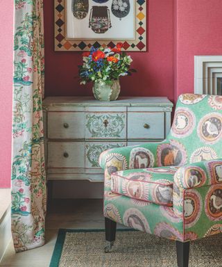 fabric patterned chair with animal eblems in green in front of sideboard with glass of flowers