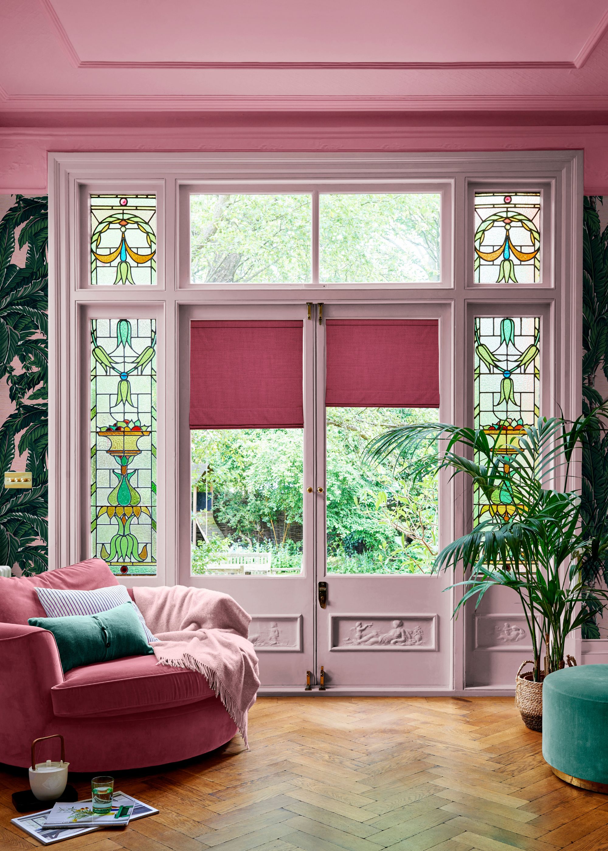 Living space with back door leading into garden, a dark pink ceiling, and light pink trim and doors, with a dark pink sofa, and parquet floors.