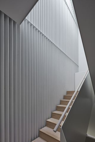 Wooden staircase featuring metal banisters, and white walls with skylight ceiling