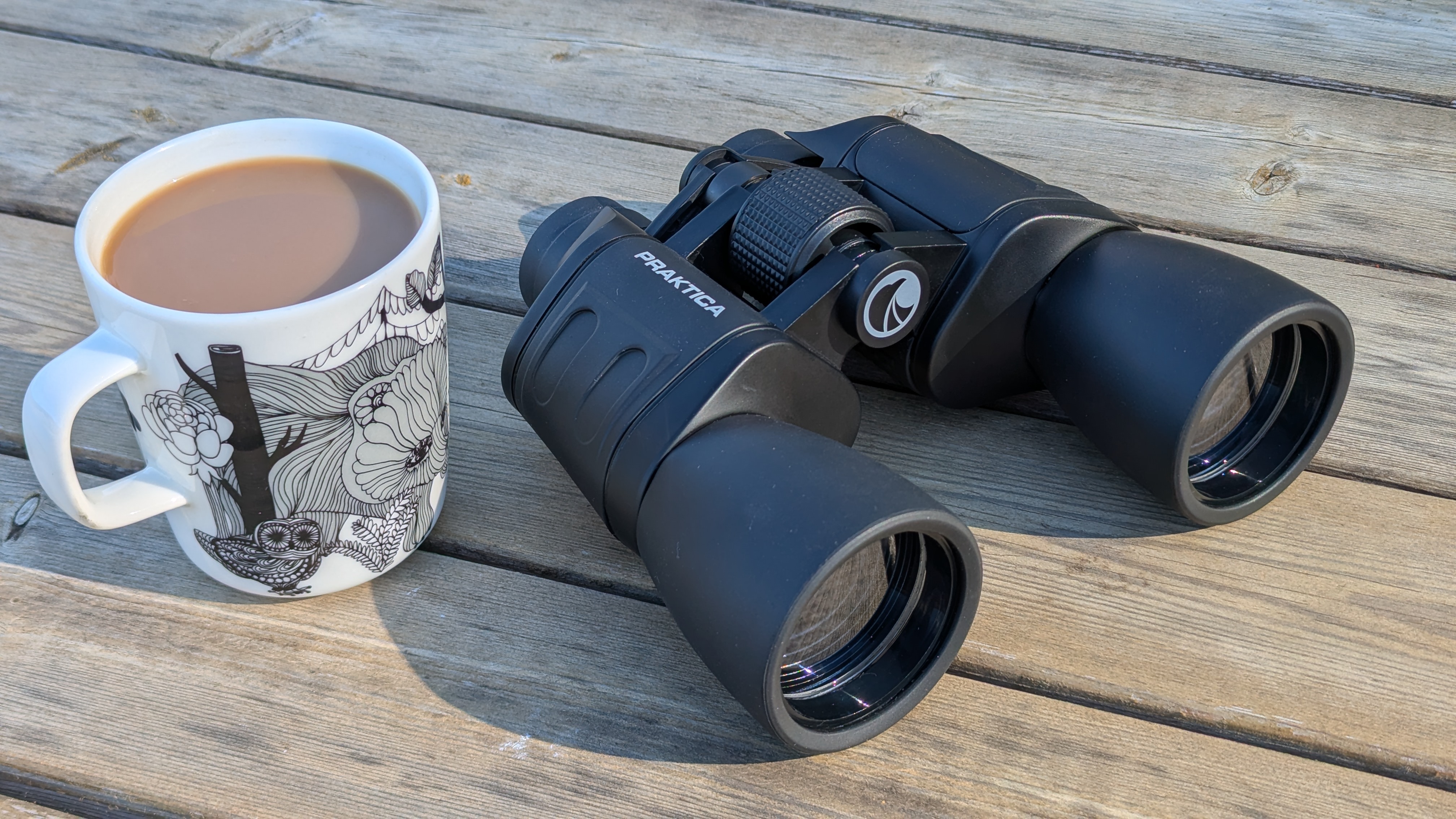 Falcon 10x50 beside a cup of coffee