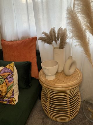 Wicker small table with ceramic pots next to sofa
