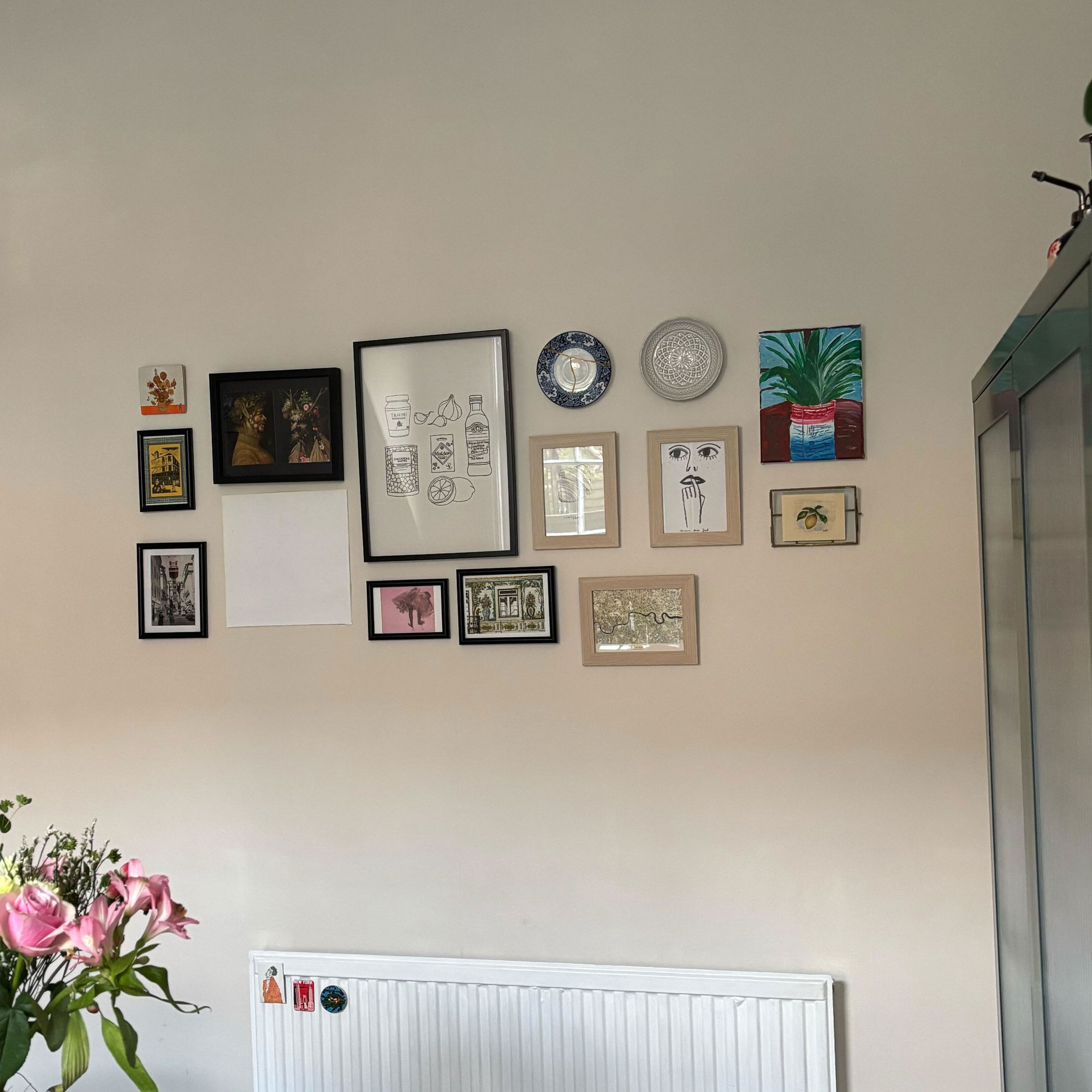 Gallery wall made up of black and wooden frames, with plates on white wall