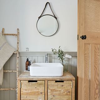 Wooden vanity unit with rectangular sink and round mirror