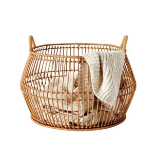 A woven storage basket with blankets in it