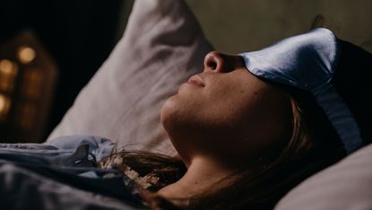 A woman in bed wearing a sleep mask
