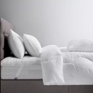 A bed with two pillows, a mattress topper, and the John Lewis Synthetic Soft Touch Washable Duvet on top