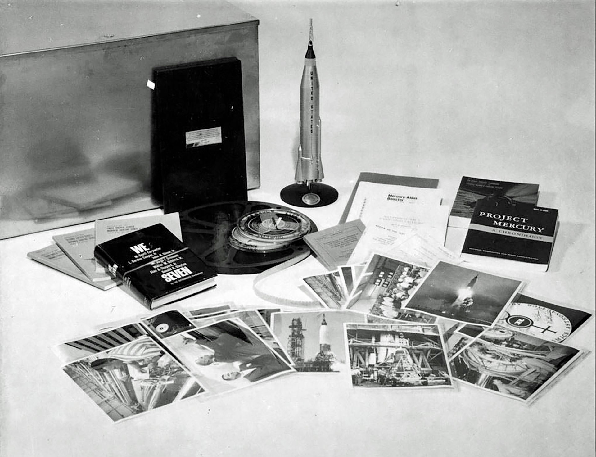 black and white photo showing a dozen or so photographs spread out on a white table