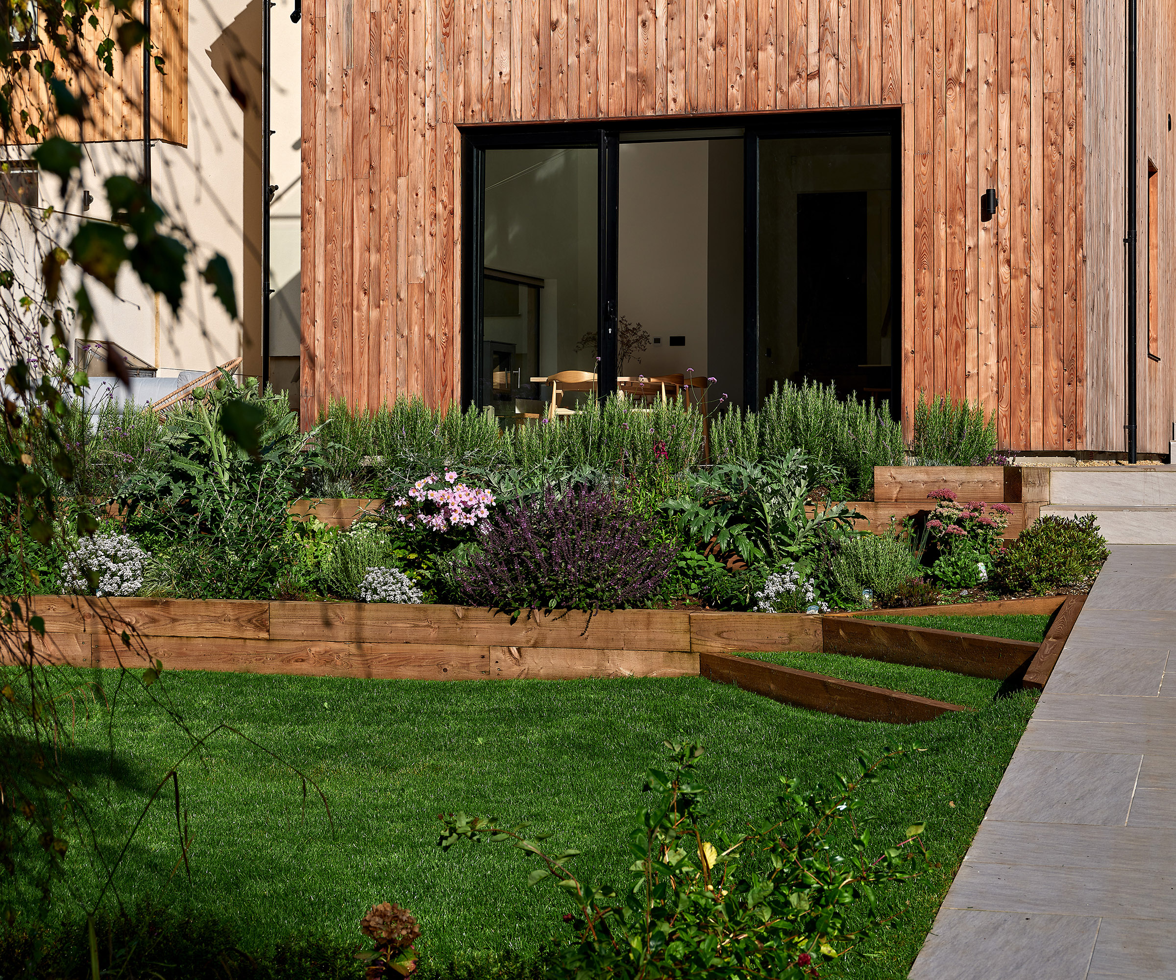 A vibrant green lawn with raised bed timber edging