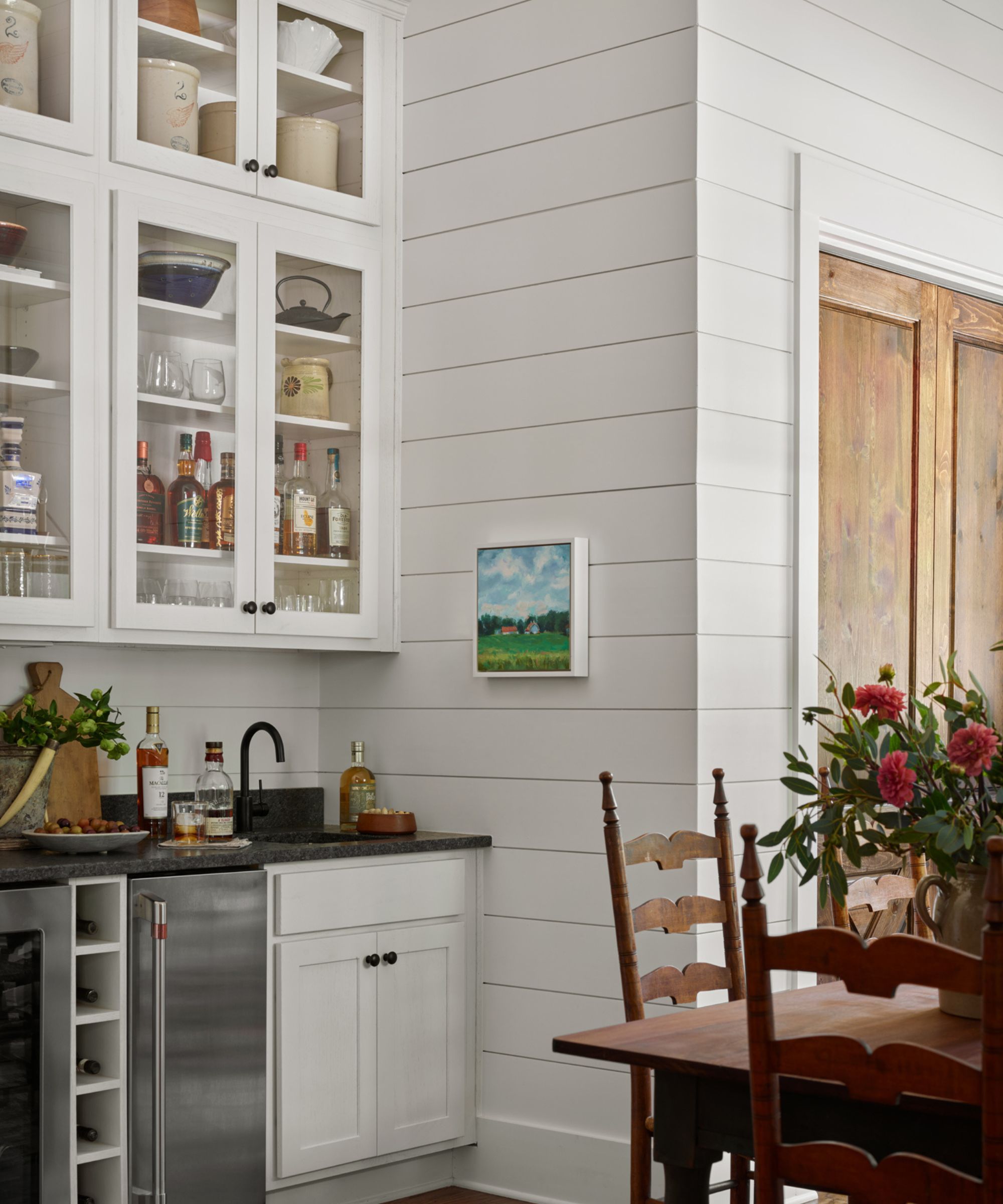 Vintage kitchen with white shiplap walls, open shelves with vintage cookware, wood dining table and chairs