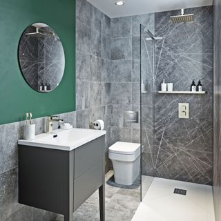 Grey shower tiles next to toilet and sink with green wall