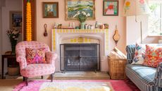 eclectic living room ideas colorful living room with pink and yellow rug, blue patterned couch, cushions, pink upholstered chair, artwork, fireplace that's painted, paint