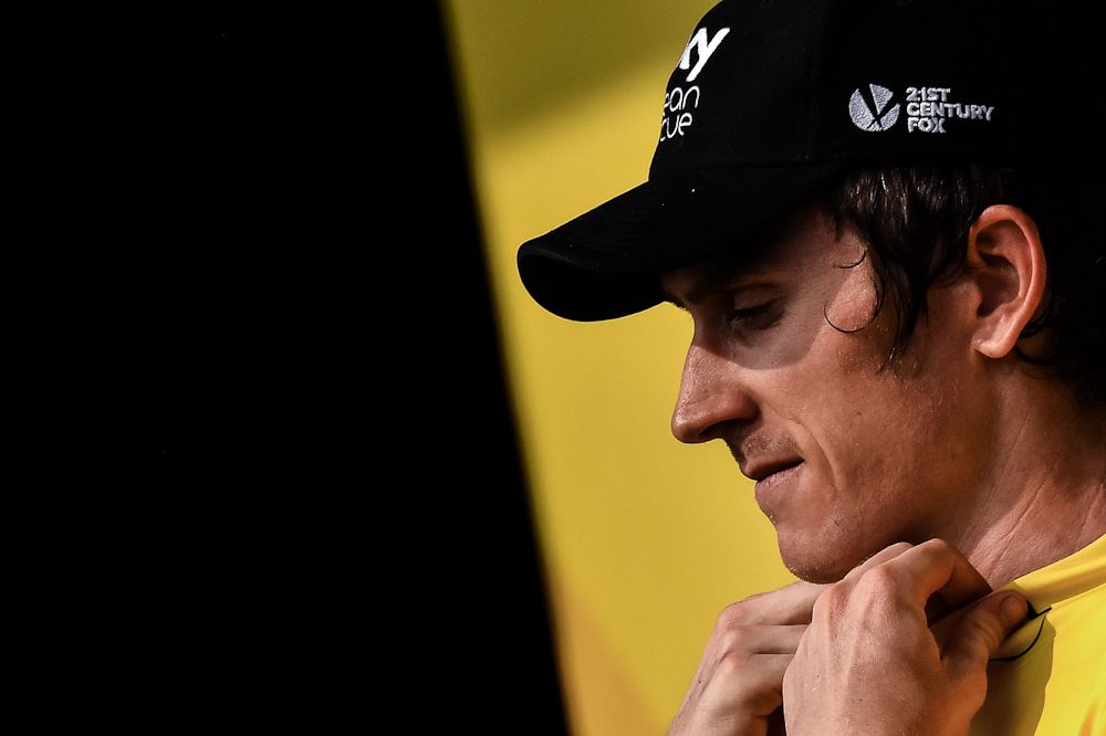 Geraint Thomas adjusts the collar of his yellow jersey after stage 18