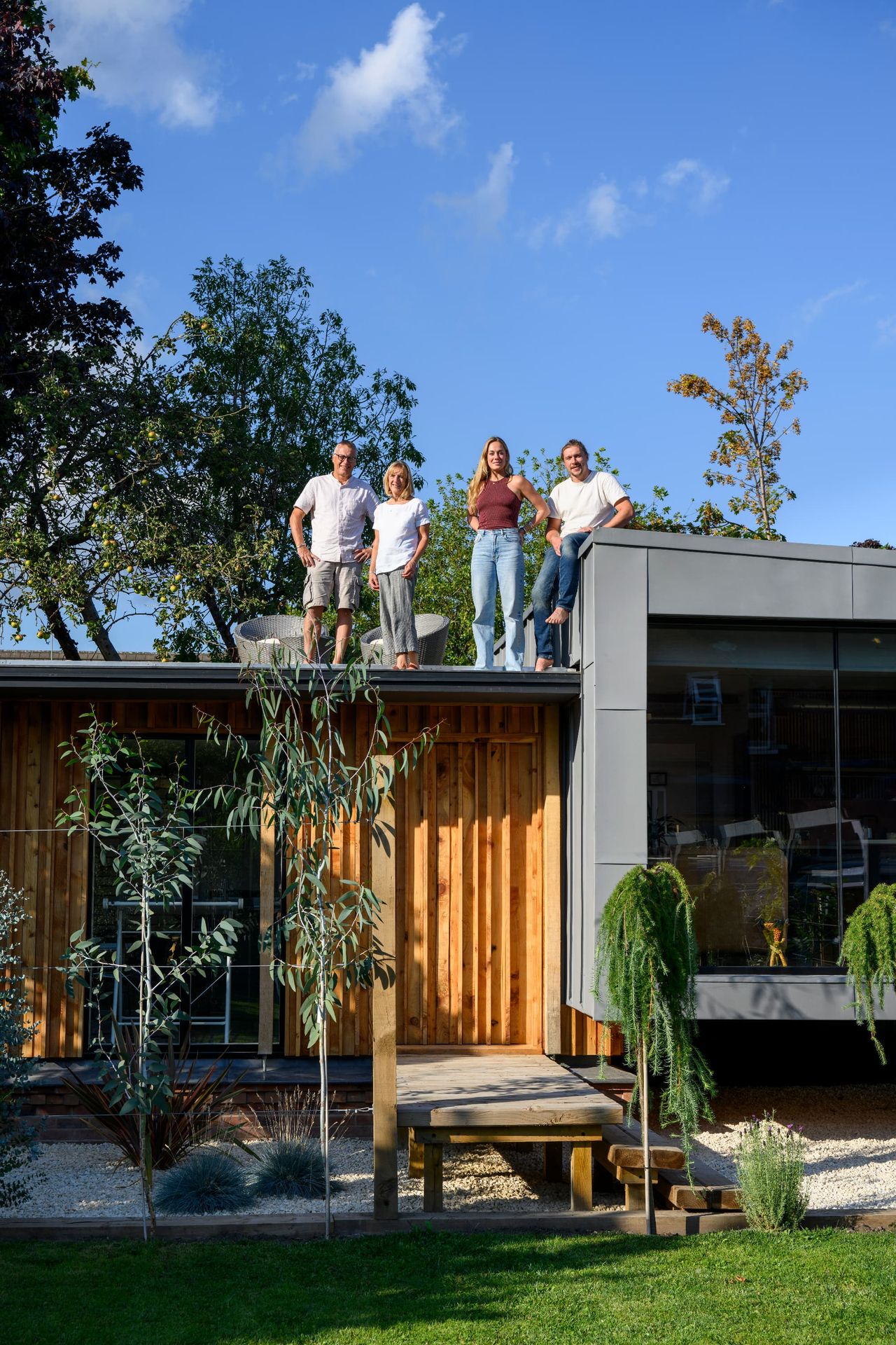 A family stand on their self-built tiny home which is clad in timber