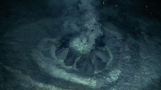 A picture of the small mud volcano spewing a muddy liquid.