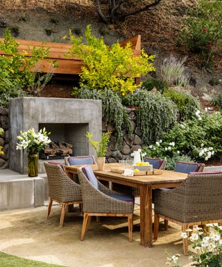 outdoor eating area with fireplace and dining table and landscaped backyard