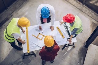 people in hard hats looking at plans