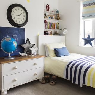 kids bedroom with white walls wooden table with drawer and globe