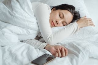 Woman sleeping in bed with smartphone by her side