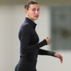 Hailey Bieber wearing a black zip up jacket with black leggings and brown sneakers