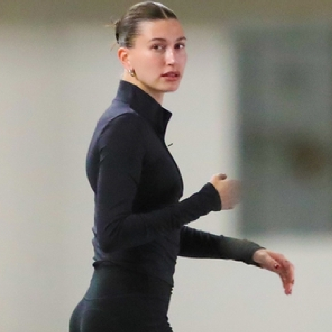 Hailey Bieber wearing a black zip up jacket with black leggings and brown sneakers