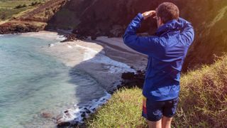 Rear view of man looking at ocean from top of cliff 