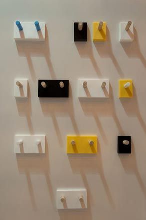 multiple coat pegs in didfferent colours and sizes displayed on a whit wall