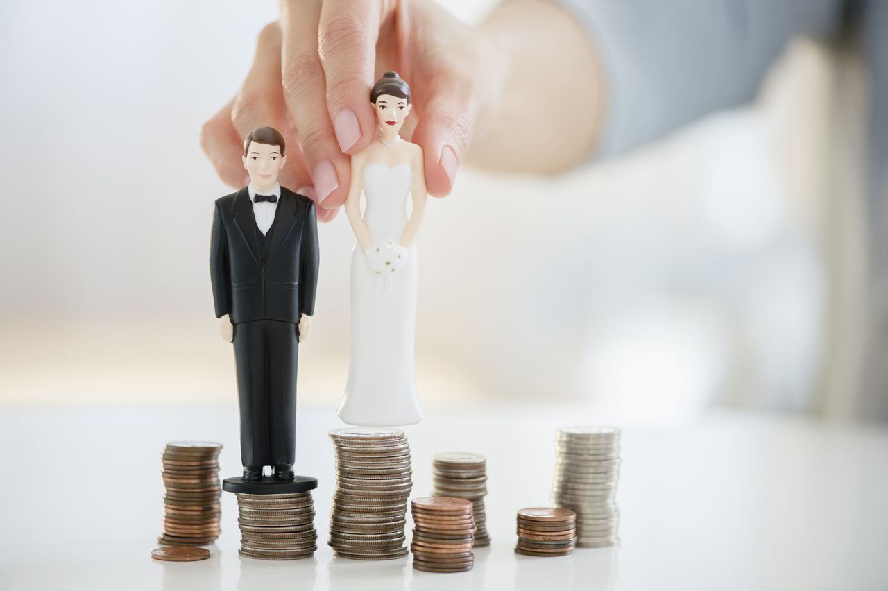 Bride and groom statues balancing on coin stacks