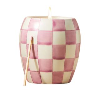 A pink and white chequered lit candle with a match