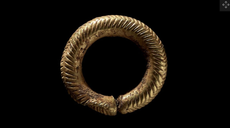 The small, gold ring displays an intricate chevron and herringbone pattern. 