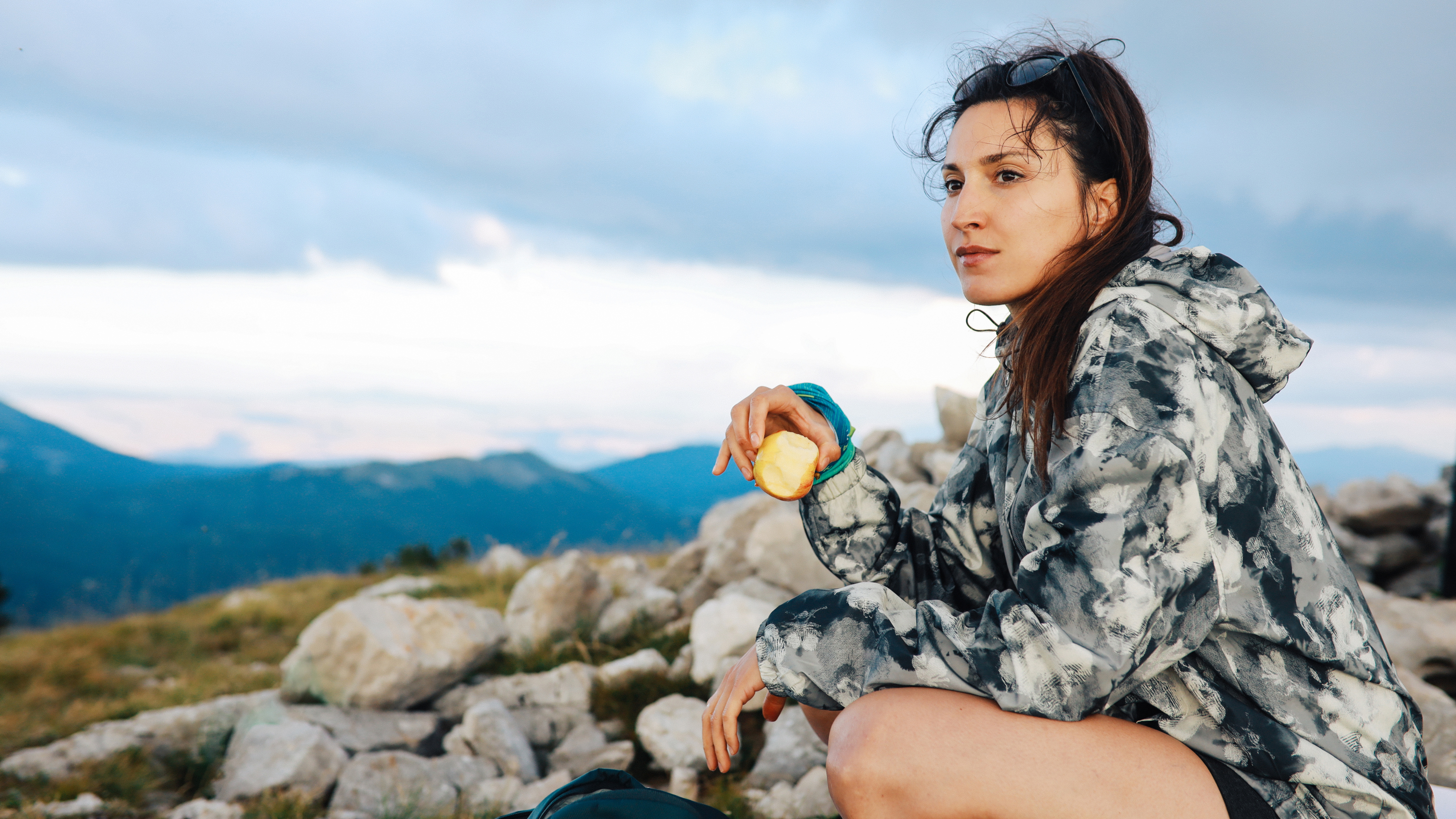 a woman eating an apple surrounded by hills