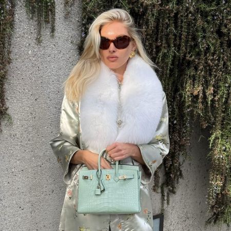 Model Elsa Hosk wears a fur-trimmed ornate knee-length jacket wth stovepipe jeans and white pointed-toe heels.