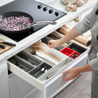 Drawer under hob pulled out to show drawer organiser for utensils