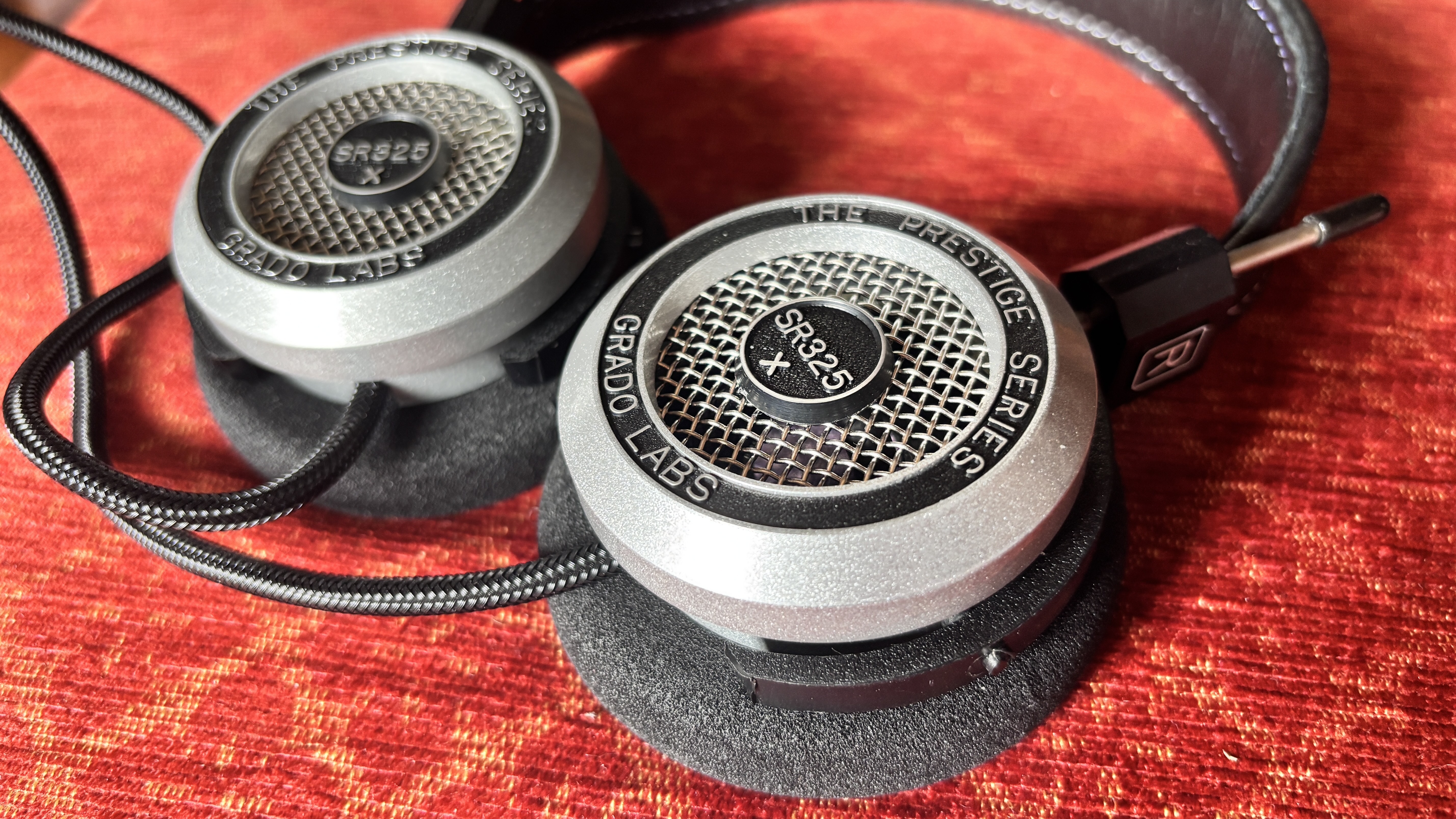 Grado SR325x wired on-ear headphones on a red fabric surface