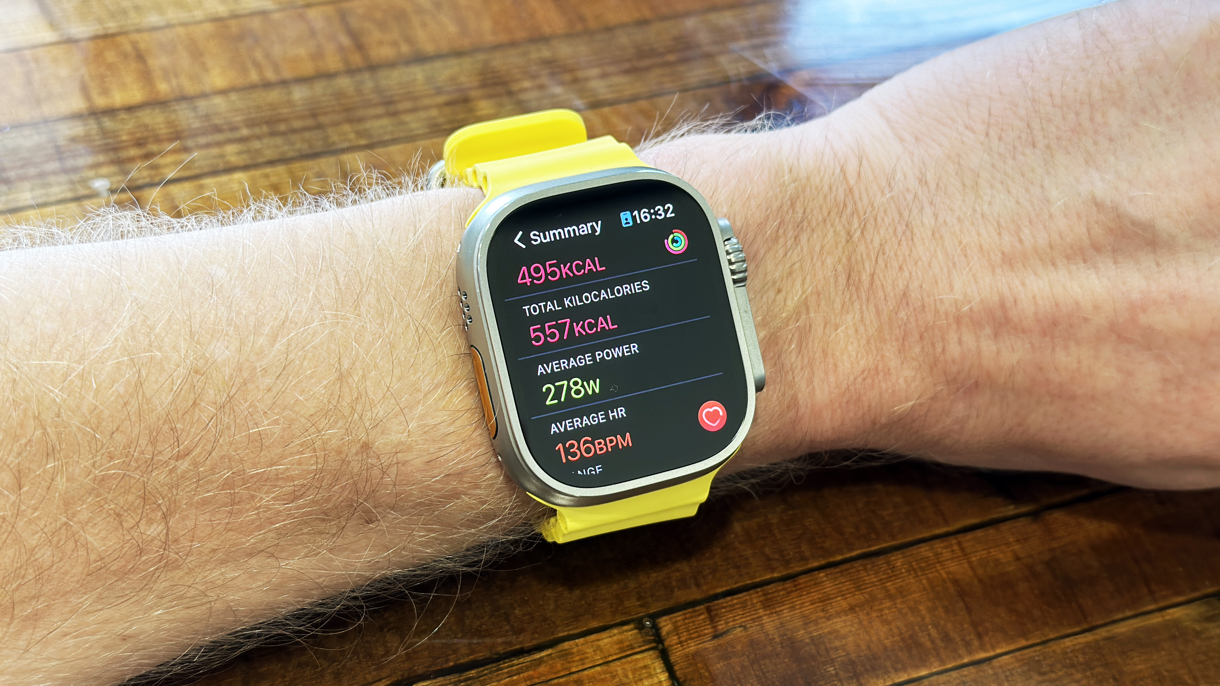 Apple Watch Ultra with yellow strap in use on wrist and on table