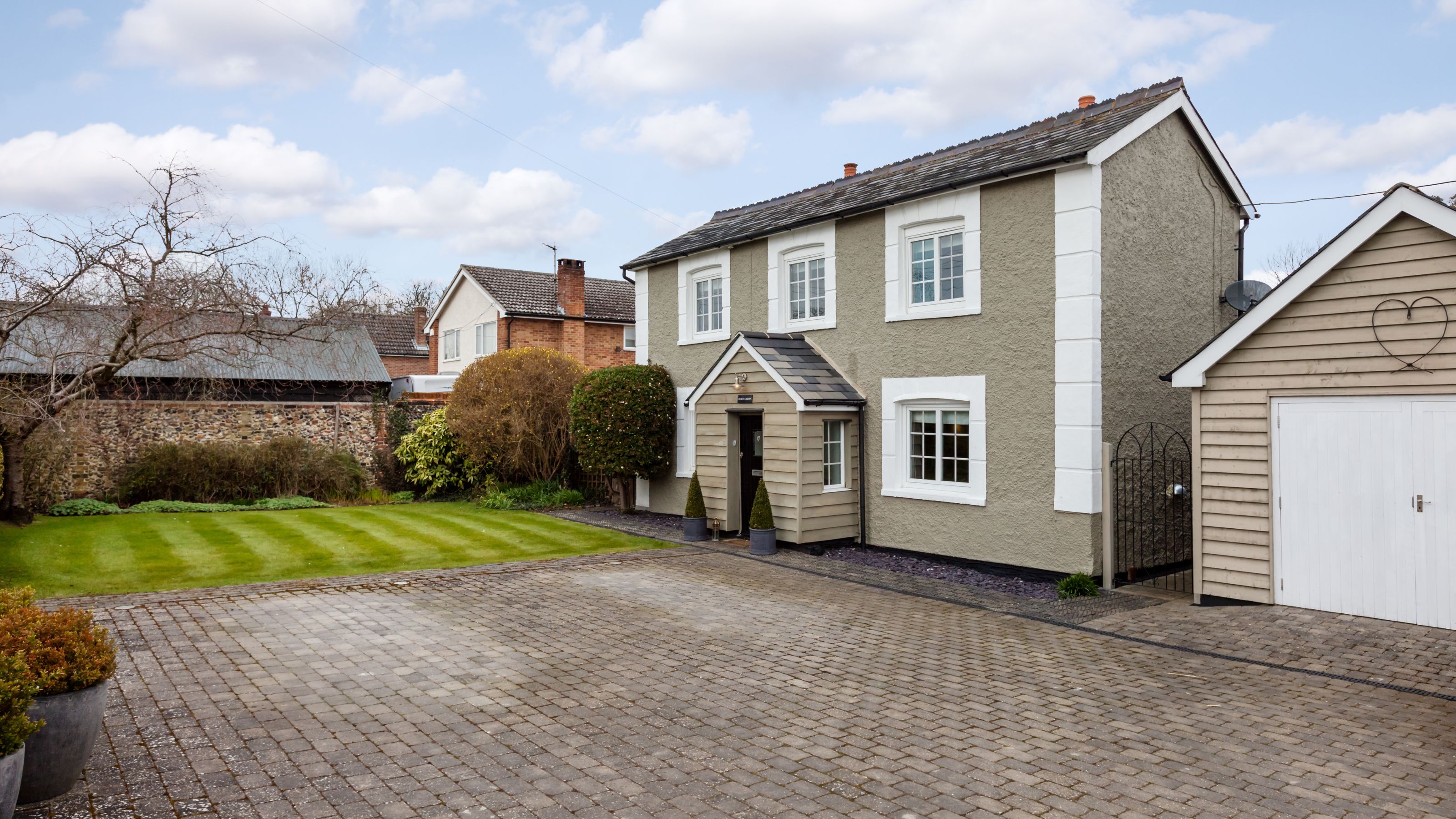 Block paving drive in front of house with clad porch and garage