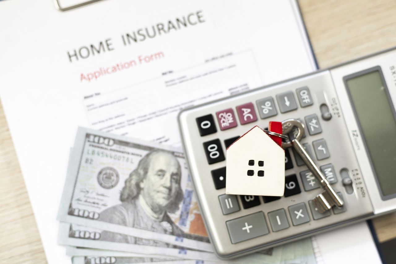 Home insurance application form, calculator and money on the desk. 